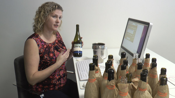 Lady holding bottle of wine next to computer